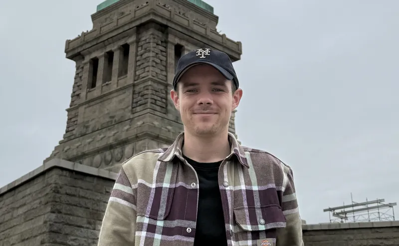 Matthieu Elloy, fondateur de Pixelle, souriant devant le socle de la statue de la Liberté